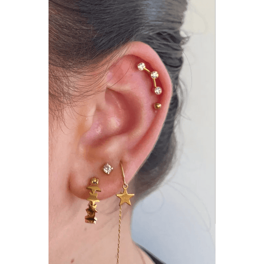 Een vrouw draagt een gouden oorketting met sterren en maanbedels