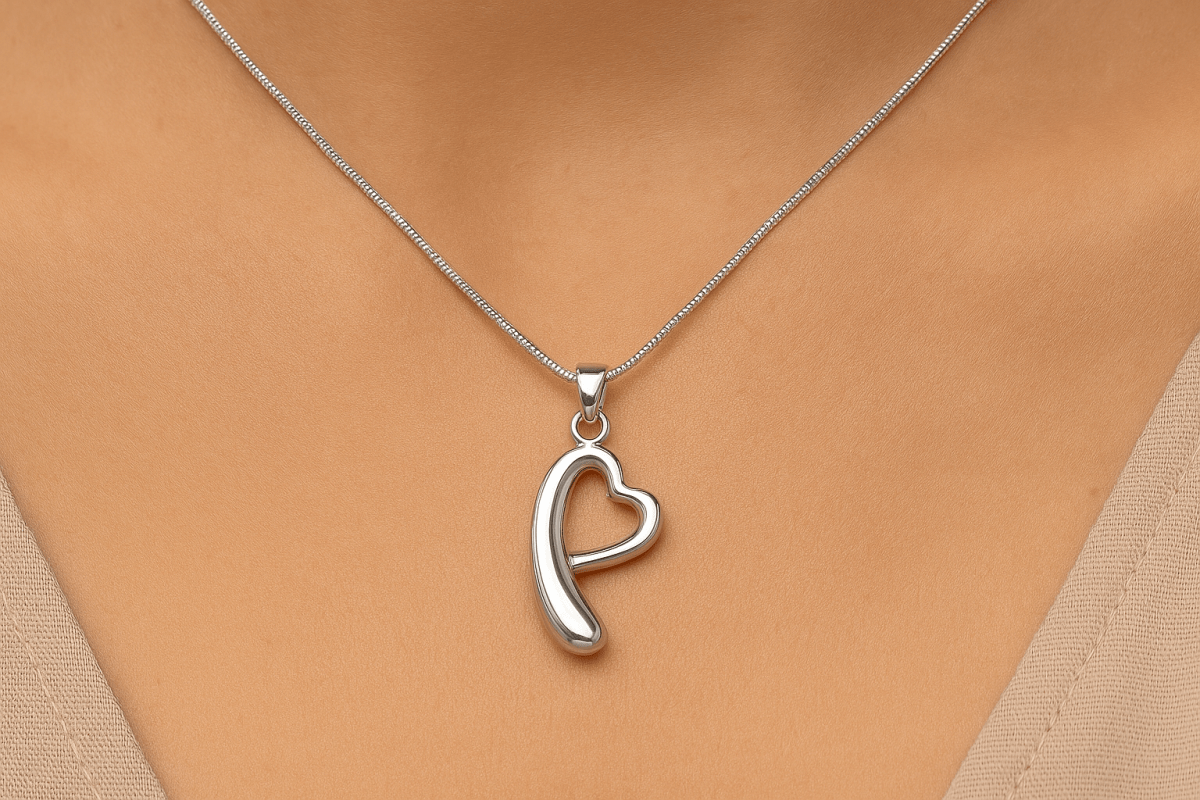 Een zilveren ashanger met een uniek ontwerp van 38x18mm met een hartvorm en gebogen element, gedragen om een vrouwelijke hals op een zilveren slangenketting.