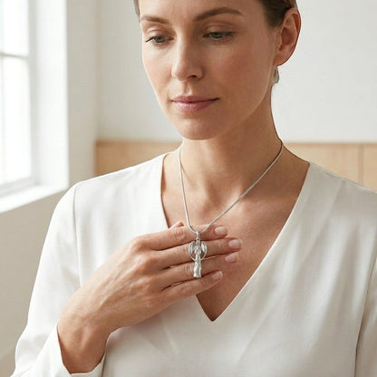 Aramat Jewels silver-colored stainless steel angel ash pendant worn by a woman. This memorial jewelry is water-resistant and suitable for daily wear.