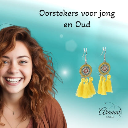 Lachende vrouw met Aramat Jewels boho oorhangers met gele kwastjes, RVS en emaille details voor een zomerse look.