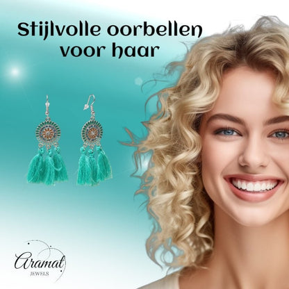 Aramat Jewels boho oorhangers met mintgroene kwastjes en RVS details naast een lachende vrouw met blond krullend haar.