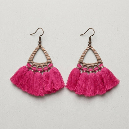 Aramat Jewels boho oorhangers met fel roze kwastjes en een bronskleurig metalen frame in een driehoekig design.