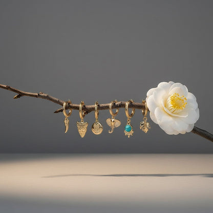 Aramat Jewels set of 6 gold-plated hoop earrings with animal charms: horn, leopard, owl, elephant, turquoise stone, and leaf.
