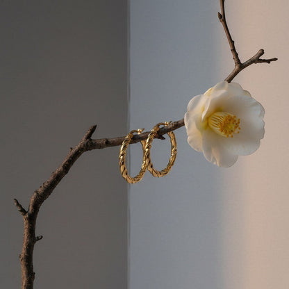 Aramat Jewels gold-tone stainless steel twisted hoop earrings, 35mm diameter, with a swirl design.