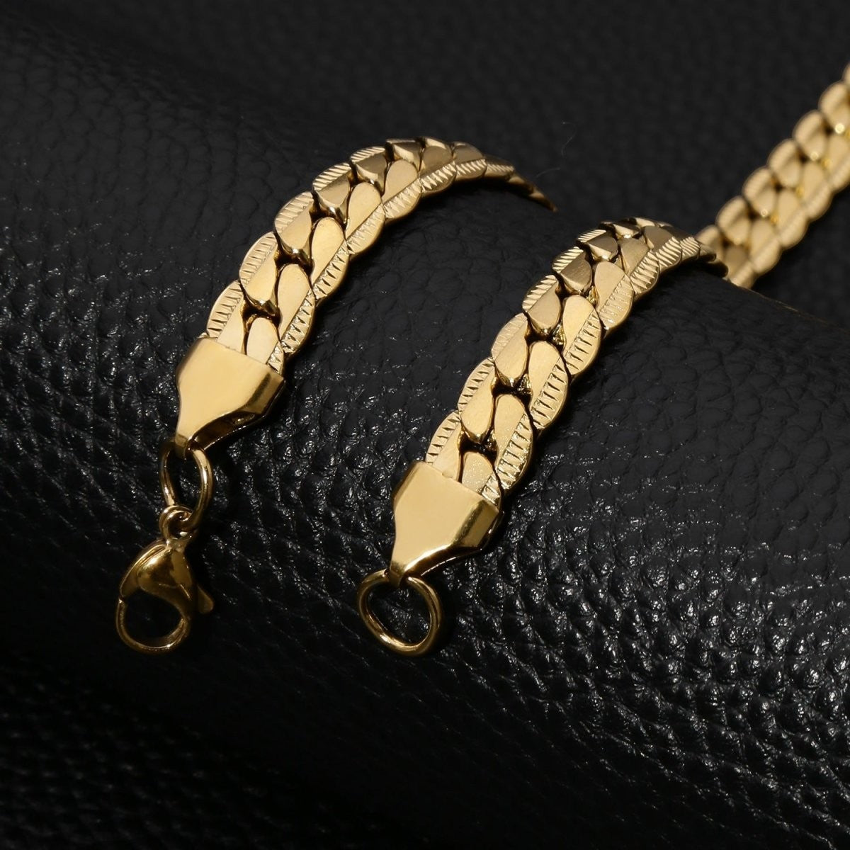 Aramat Jewels goudkleurige stalen gourmet ketting van 6mm breed met een unieke bewerkte rand op een zwarte ondergrond.