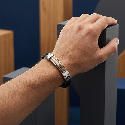 Aramat Jewels herenarmband van zwart leer en RVS met goud- en rosékleurige accenten om een pols.