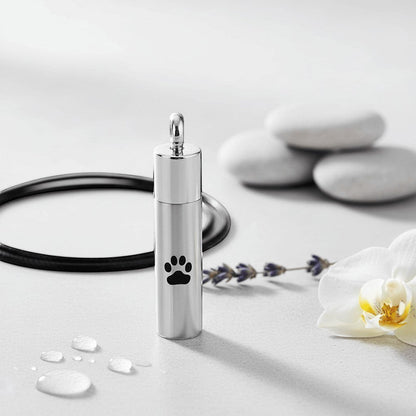 Aramat Jewels matte silver stainless steel cremation urn pendant with black paw print design. 46mm tube shape with screw top.