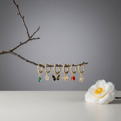 Aramat Jewels set of 6 gold-plated 925 silver hoop earrings with nature-themed charms: green marquise gem, white flower, black butterfly, bee, ladybug, and pink flower.