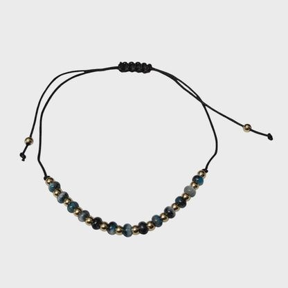 Aramat Jewels verstelbaar enkelbandje met blauwe cats eye kralen en gouden accenten op een zwart touwtje.