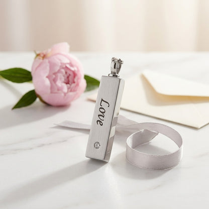 Aramat Jewels vierkante buis ashanger van RVS in zilverkleur met de tekst 'Love' en een zirkonia. Een romantisch gedenksieraad.