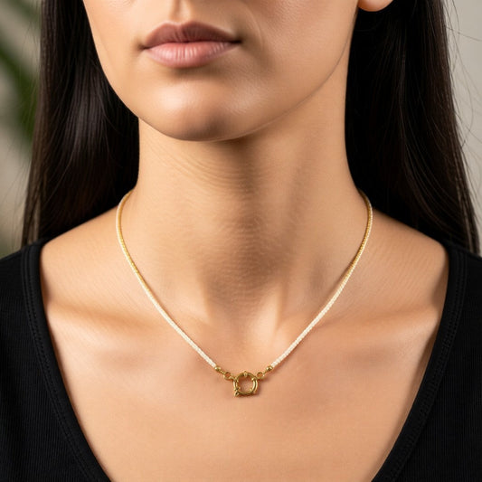 Aramat Jewels white Rocailles bead necklace with gold-tone clasp on a woman wearing a black top.