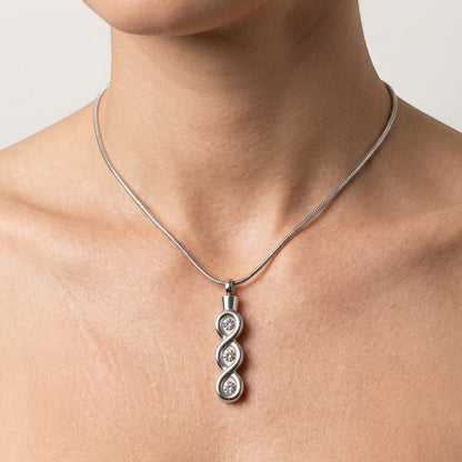 Aramat Jewels® zilverkleurige stalen crematiehanger met transparante details en drie cirkelvormige gravures.