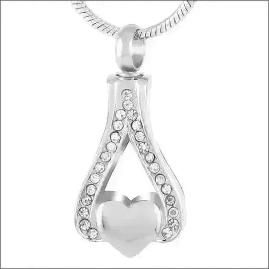 Aramat Jewels zilverkleurige stalen ashanger in hartvorm, versierd met kristallen. Een subtiel gedenksieraad.