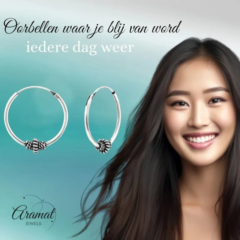 Aramat Jewels 18mm silver Bali hoop earrings with ethnic bead detail. Model with dark hair smiling.
