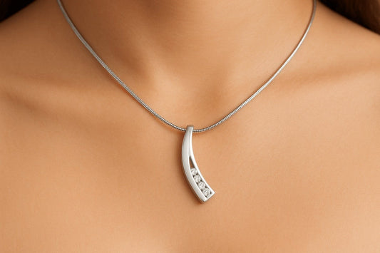 Zilveren gebogen ashanger met diamanten inleg, 33x7mm, met elegante curve en rij briljante diamanten zichtbaar door de uitgesneden binnenkant, gedragen op vrouwenhals met zilveren slangenketting.
