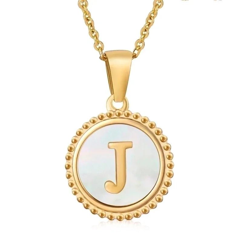 Hanger met vergulde ketting met de letter ’J’ op een parelmoeren achtergrond met kralenrand.